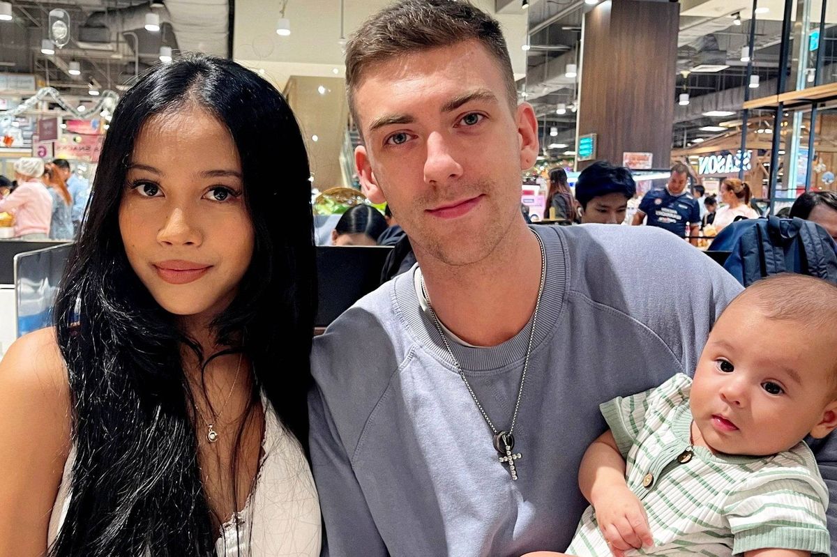 បុគ្គលពីរនាក់ ម្នាក់មានសក់ខ្មៅវែង និងម្នាក់ទៀតមានសក់ខ្មៅខ្លី កំពុងញញឹម និងថតរូបនៅកន្លែងដែលមានមនុស្សអ៊ូអរ។ បុរស​នេះ​កំពុង​កាន់​ទារក​តូច​ម្នាក់​ក្នុង​ដៃ ខណៈ​អ្នក​ទី​បី​ឈរ​នៅ​ពី​ក្រោយ​ខ្នង បន្ថែម​ភាព​រស់​រវើក។